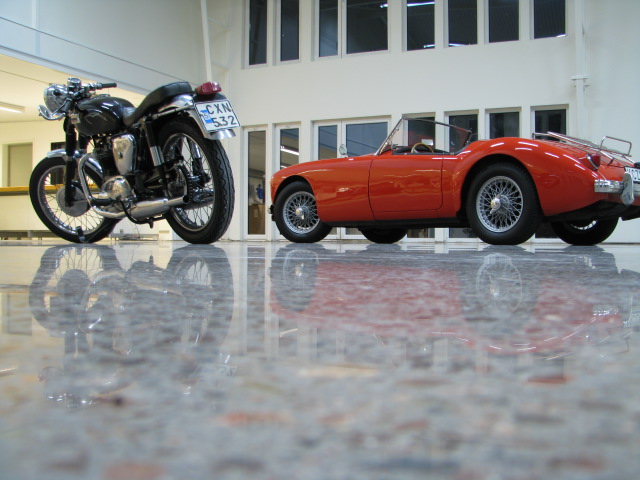Motocykel och röd bil i ett garage med nyslipad betonggolv